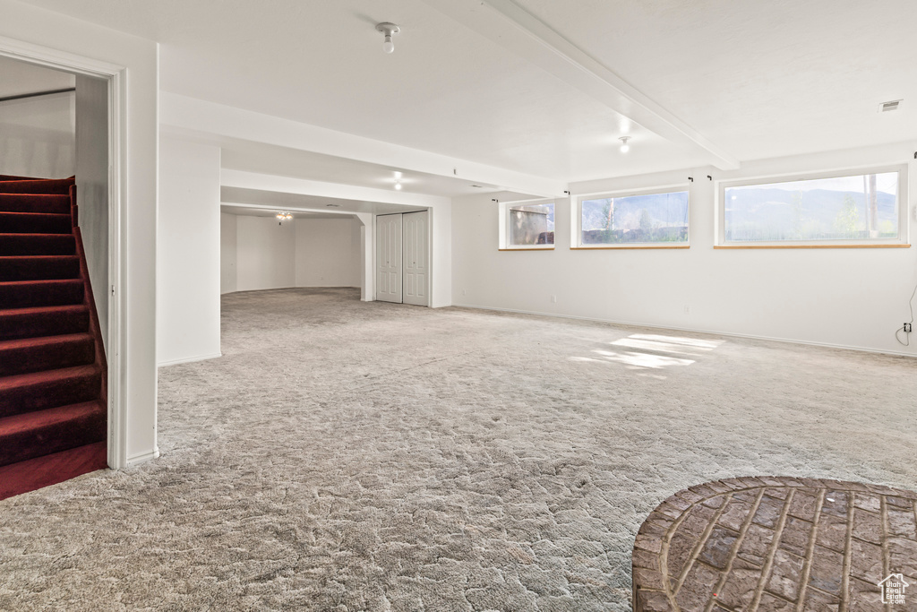 Below grade area featuring carpet, stairway, and healthy amount of natural light
