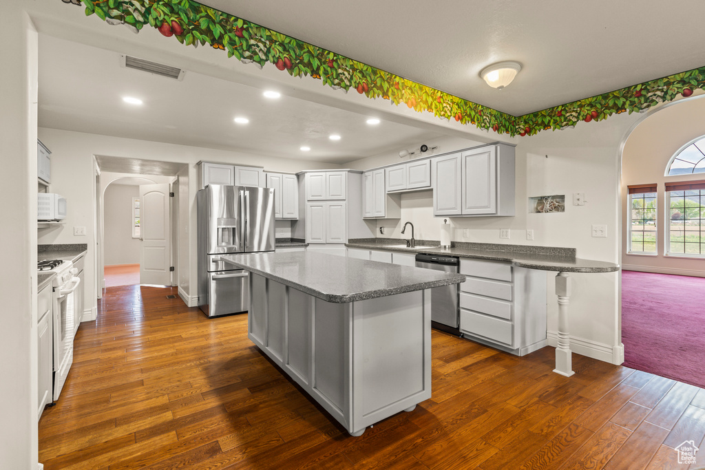 Kitchen featuring arched walkways, stainless steel appliances, baseboards, and recessed lighting