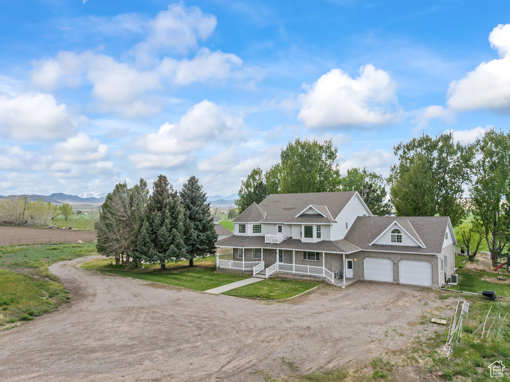 Multi unit property with covered porch, dirt driveway, a garage, and a mountain view