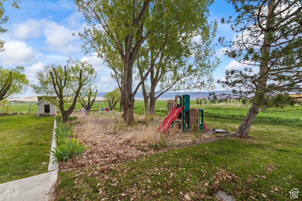 Communal playground with a yard, a view of rural / pastoral area, and an outbuilding