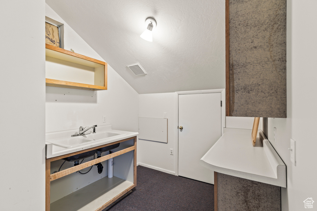Bathroom with a sink and lofted ceiling