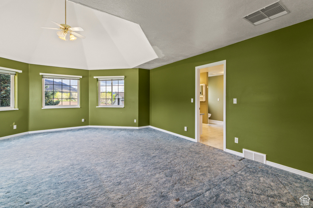 Carpeted spare room with plenty of natural light, ceiling fan, baseboards, and lofted ceiling