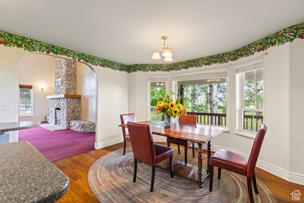 Dining space with a chandelier, healthy amount of natural light, and wood finished floors