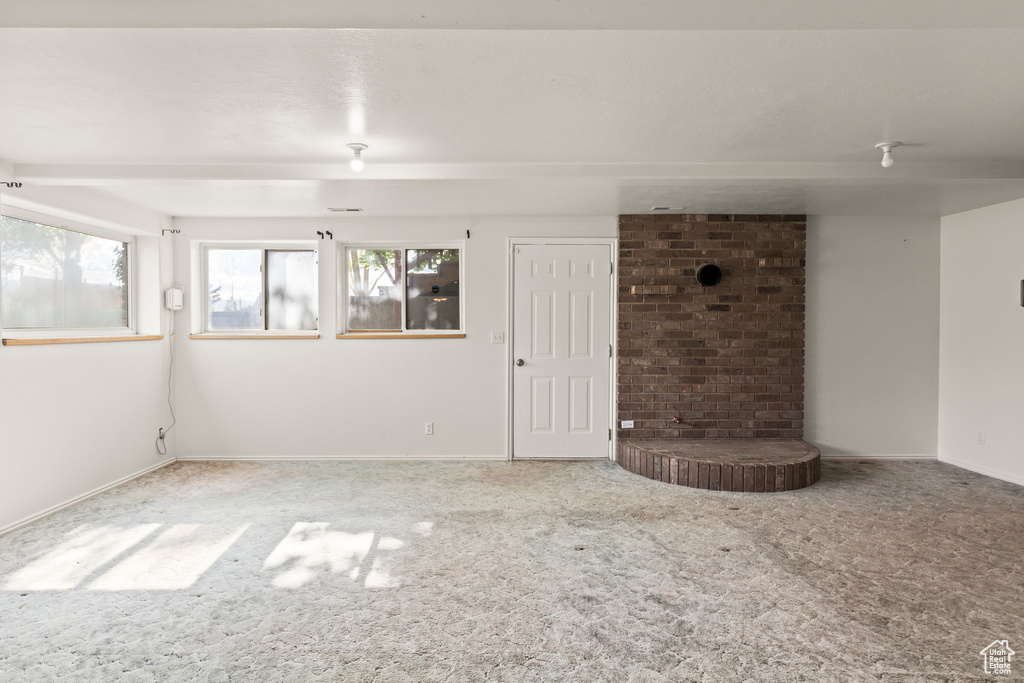 Unfurnished living room featuring carpet flooring, healthy amount of natural light, and baseboards