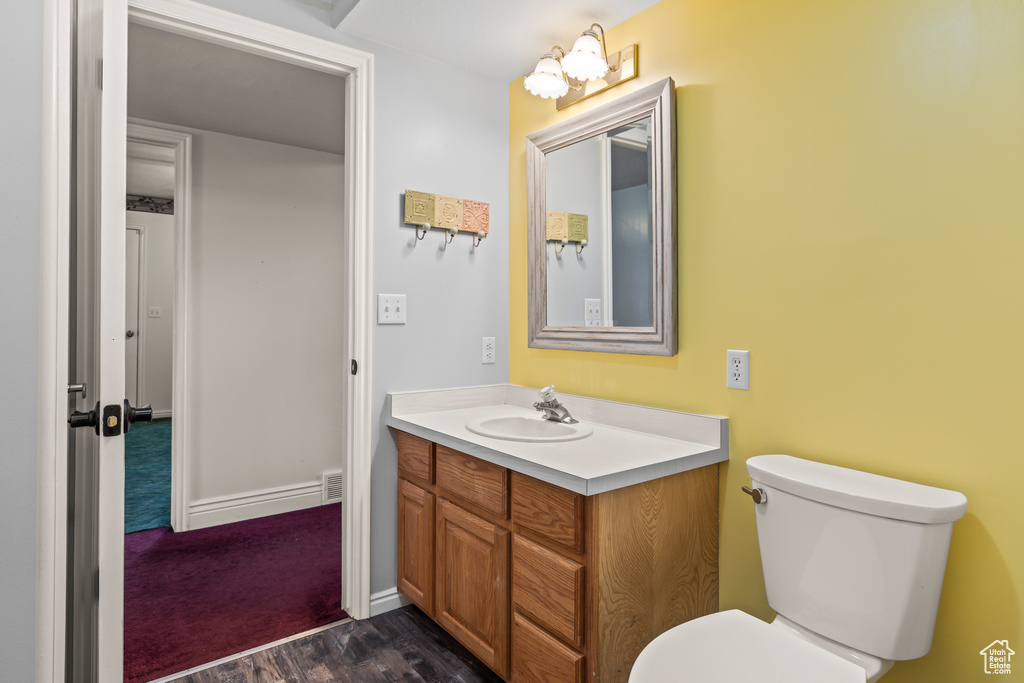 Bathroom with wood finished floors, vanity, toilet, and baseboards