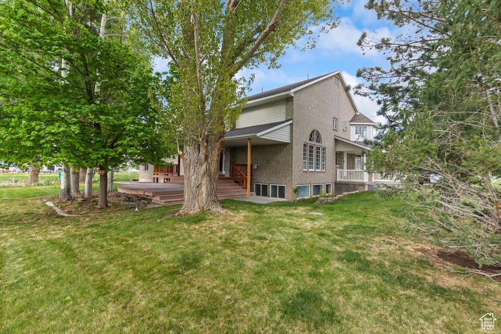 Back of property featuring a yard, brick siding, and roof with shingles