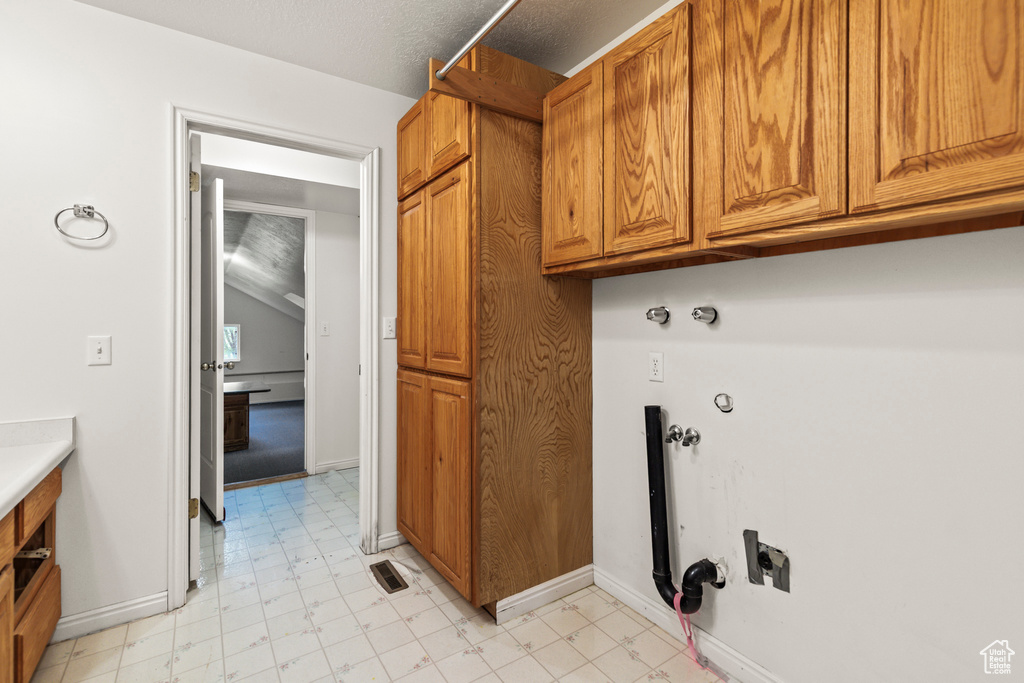 Laundry area with cabinet space, baseboards, hookup for a gas dryer, and light floors