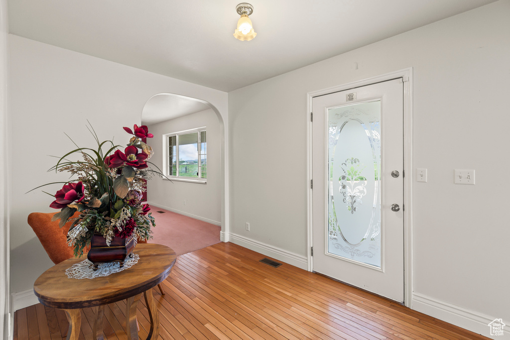 Entryway with light wood-style floors, arched walkways, and baseboards