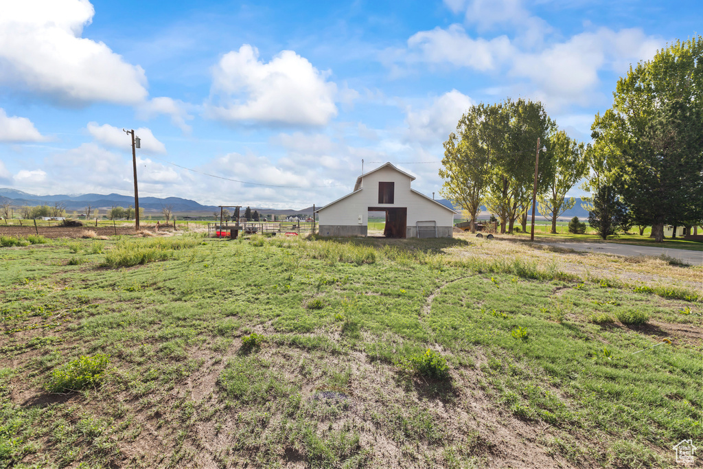 View of yard with a barn, a view of rural / pastoral area, an outbuilding, a mountain view, and fence