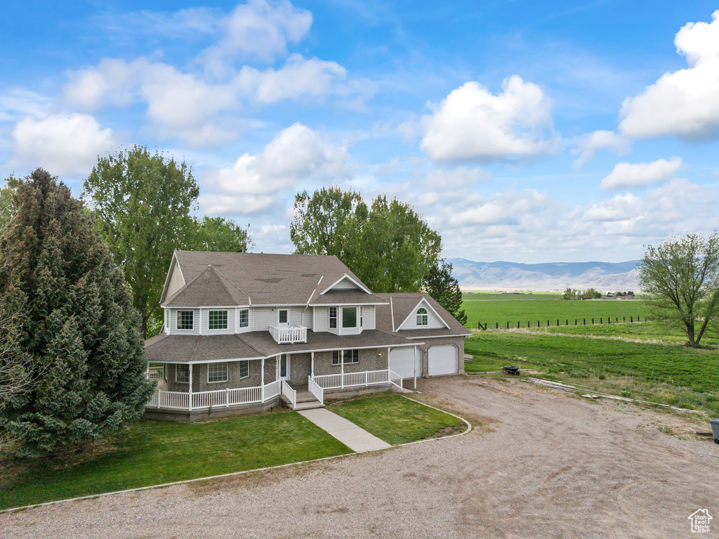 View of front of house featuring driveway, covered porch, a front yard, a shingled roof, and a garage