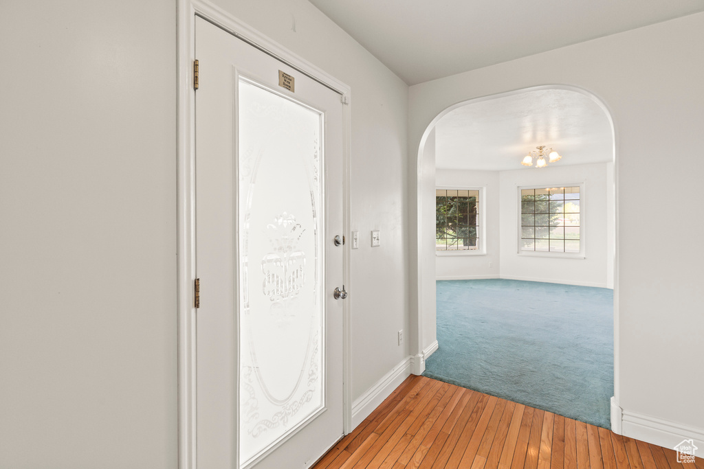 Hallway featuring arched walkways, baseboards, light wood-type flooring, and light carpet
