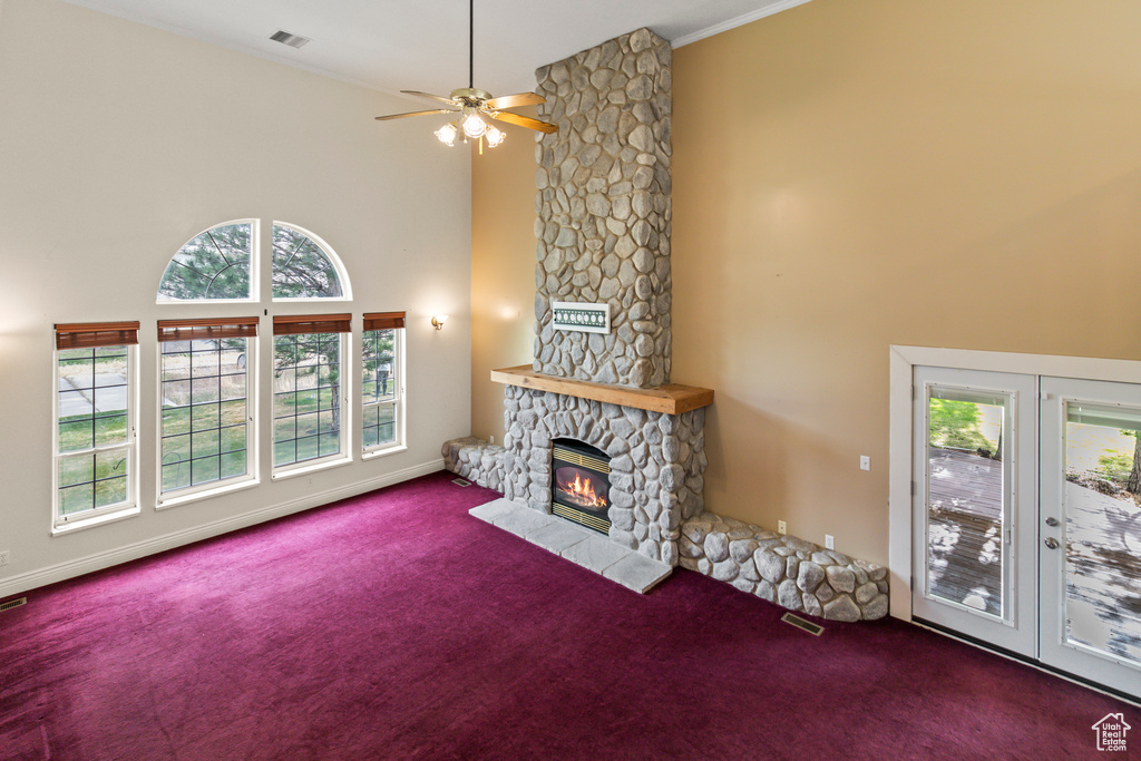 Living area featuring carpet floors, healthy amount of natural light, a fireplace, and a high ceiling