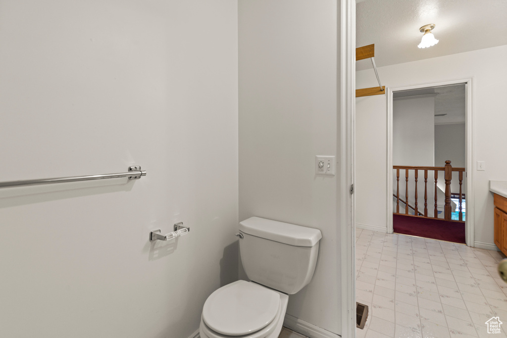 Bathroom with toilet, tile patterned floors, baseboards, and vanity