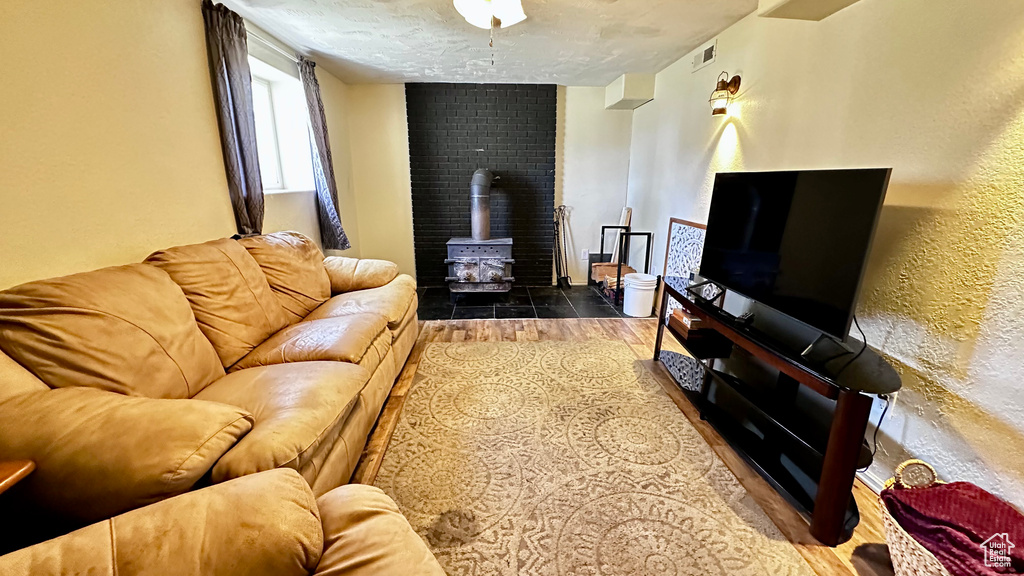 Living area with a wood stove, wood finished floors, a textured ceiling, and a textured wall