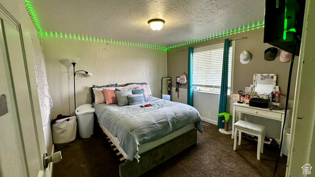 Bedroom with a textured ceiling and dark carpet
