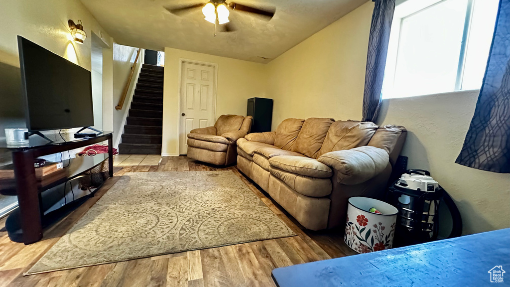 Living room with stairway, ceiling fan, and wood finished floors