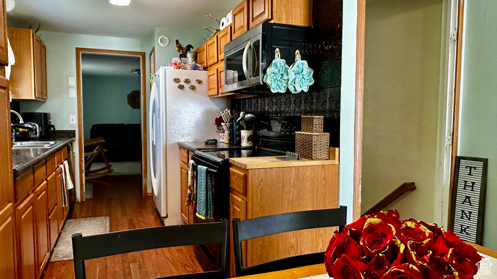 Kitchen featuring a sink, light wood-type flooring, stainless steel microwave, and brown cabinetry