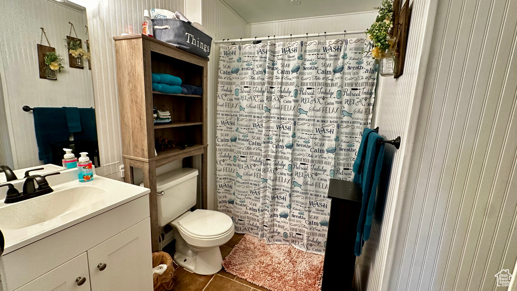 Bathroom featuring tile patterned floors, toilet, vanity, and curtained shower