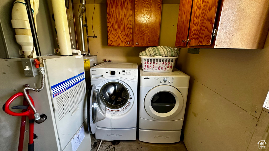 Washroom with washing machine and clothes dryer, cabinet space, and heating unit