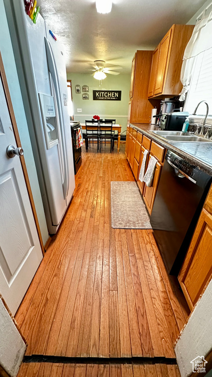 Kitchen featuring dishwasher, a sink, light wood finished floors, brown cabinets, and white refrigerator with ice dispenser