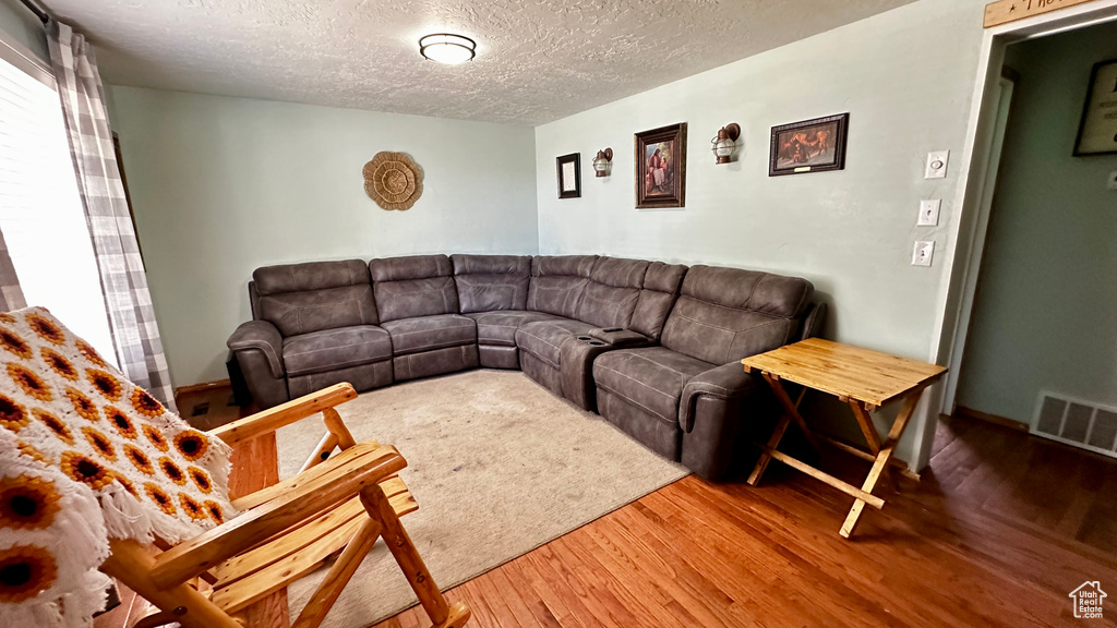 Living room with wood finished floors, a textured ceiling, and baseboards