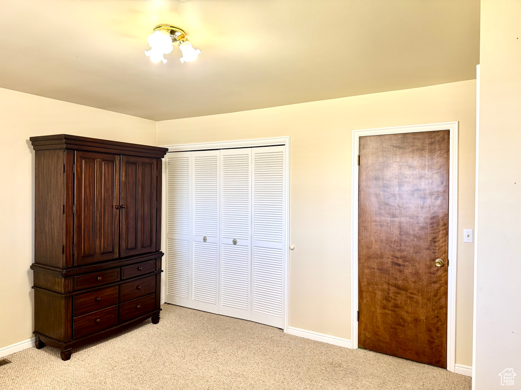 Unfurnished bedroom with light colored carpet, baseboards, and a closet