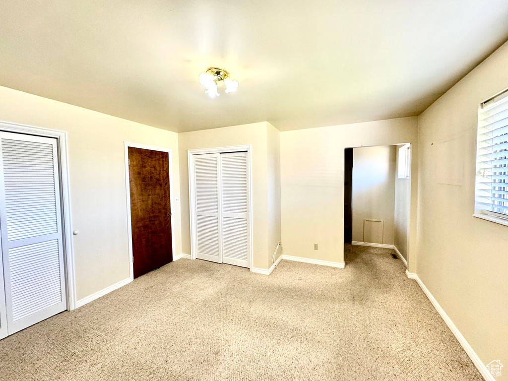 Unfurnished bedroom with carpet flooring, multiple closets, and baseboards