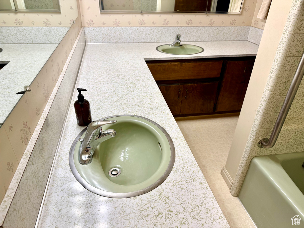 Full bath featuring wallpapered walls and vanity