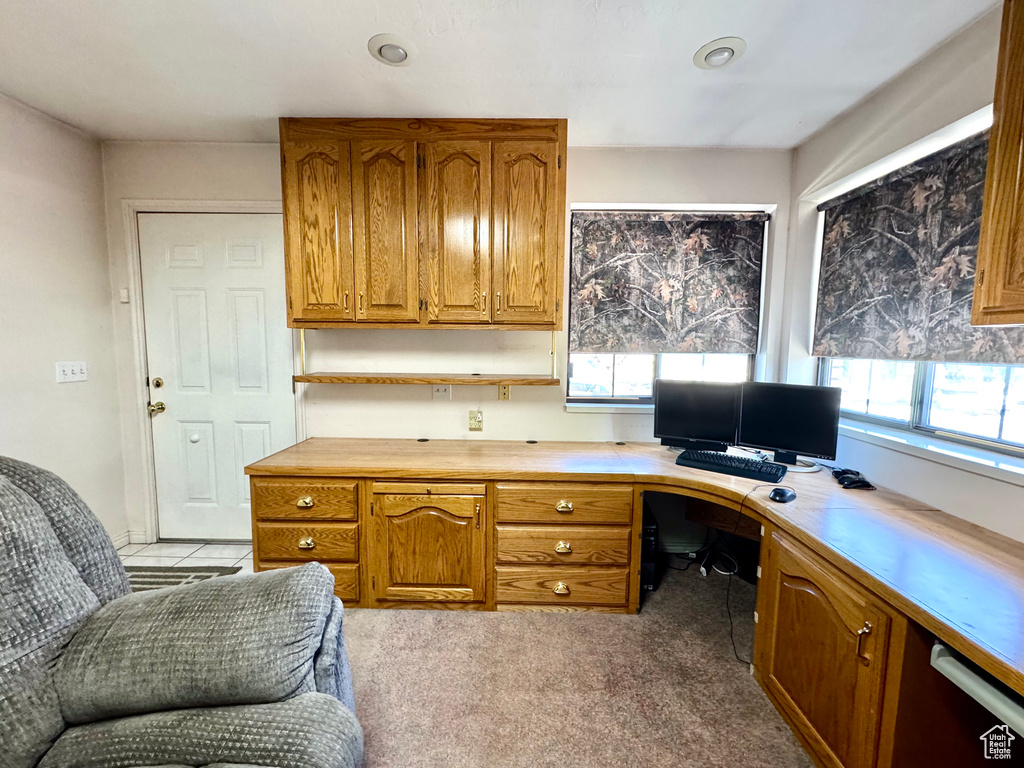 Office space featuring healthy amount of natural light, built in desk, and light colored carpet