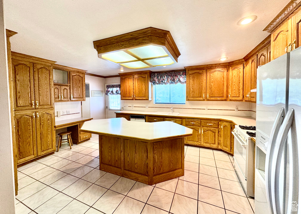 Kitchen with white appliances, a sink, brown cabinets, light countertops, and recessed lighting