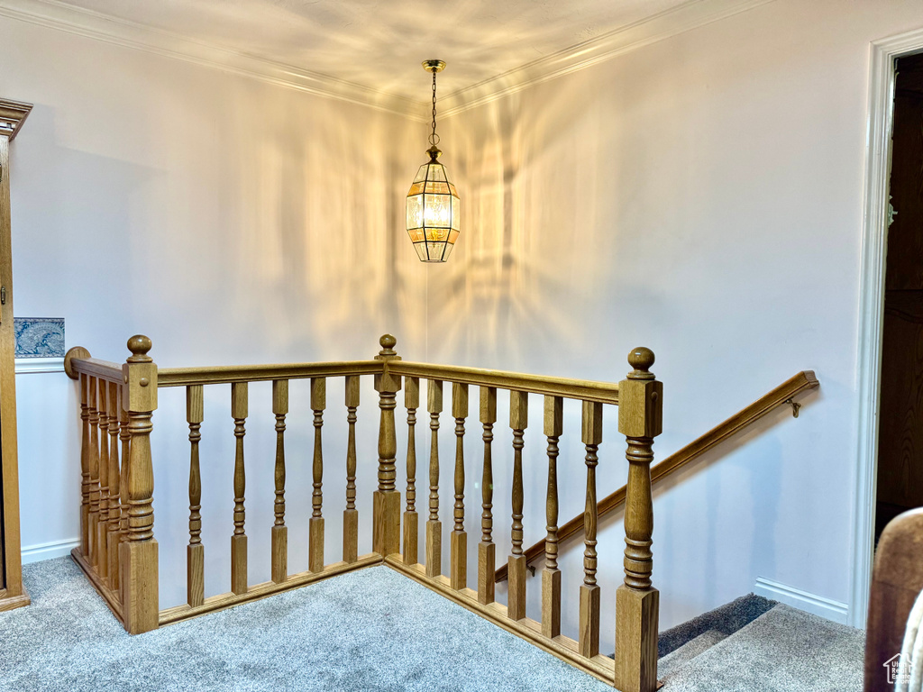 Staircase featuring carpet, a chandelier, ornamental molding, and baseboards