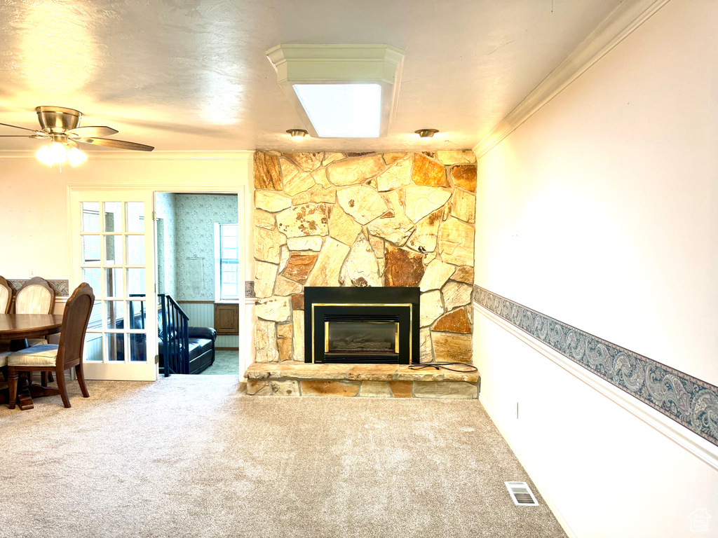 Living area featuring ornamental molding, carpet flooring, a fireplace, and a ceiling fan