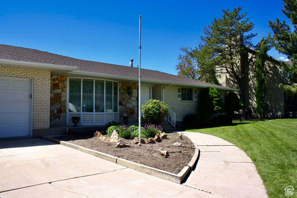 View of front of home with a front yard, brick siding, an attached garage, and roof with shingles