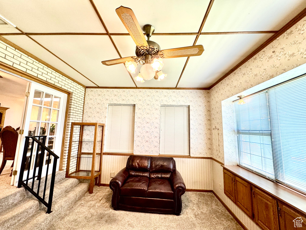 Living area with plenty of natural light, wallpapered walls, crown molding, a ceiling fan, and light carpet