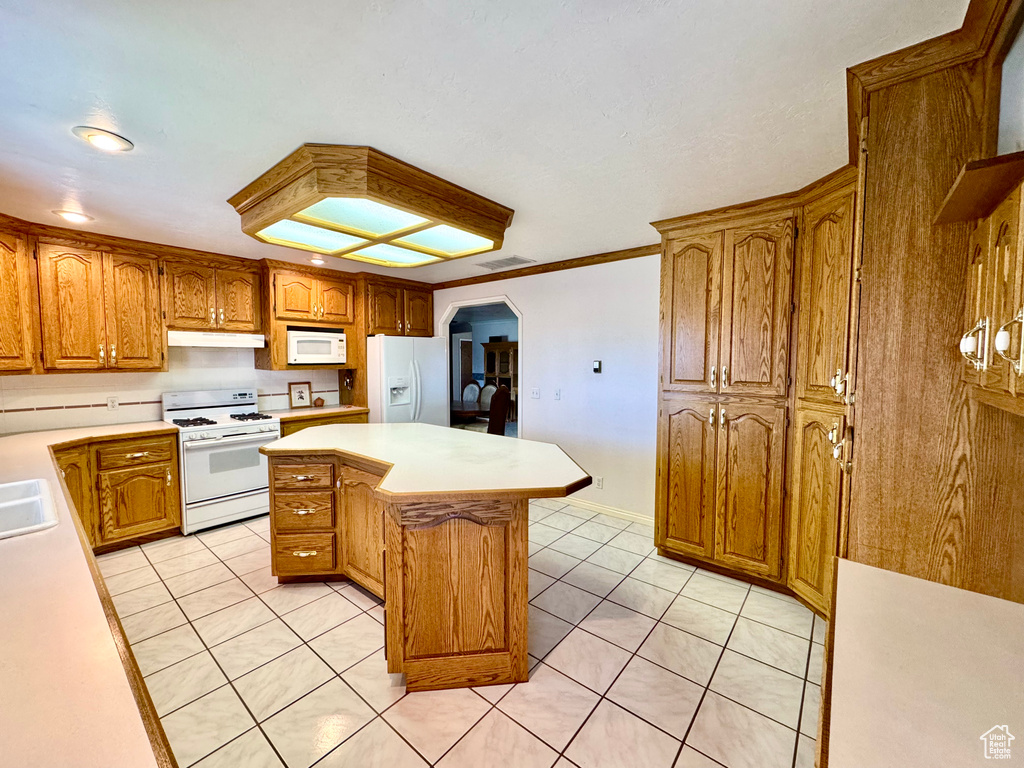 Kitchen featuring white appliances, light tile patterned flooring, light countertops, and arched walkways