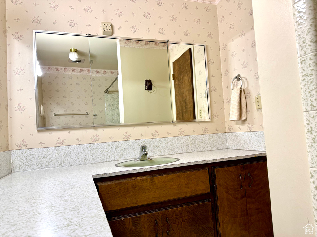 Bathroom featuring wallpapered walls, vanity, and a shower