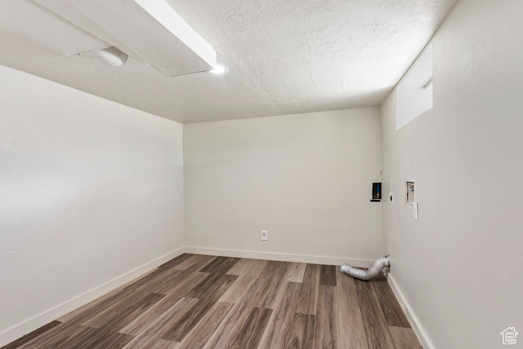 Empty room featuring wood finished floors, baseboards, and a textured ceiling
