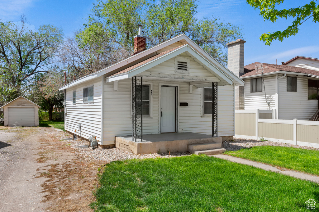 View of front of house featuring a chimney, an outdoor structure, driveway, a porch, and a garage