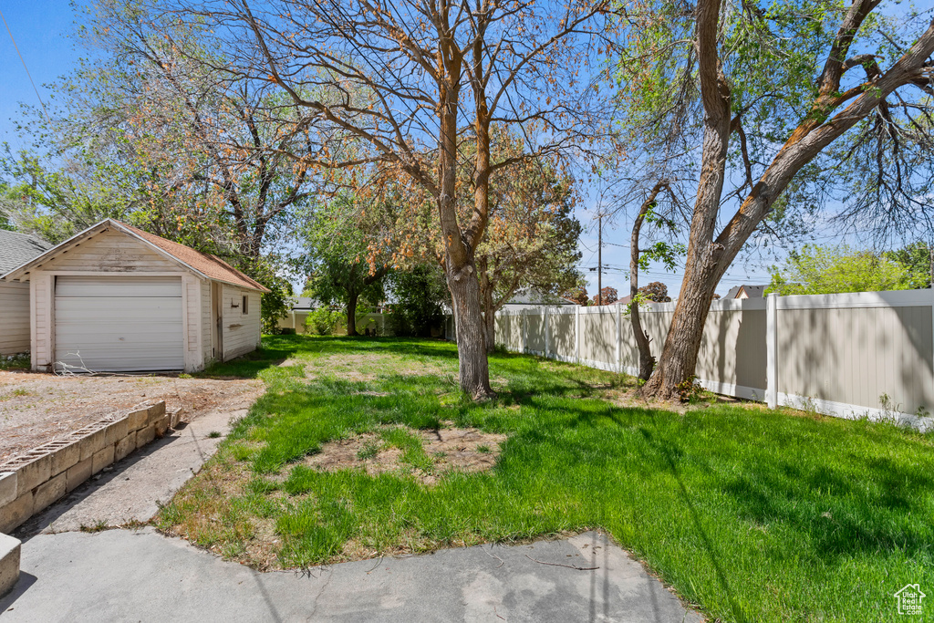 View of yard with a garage, an outbuilding, and driveway