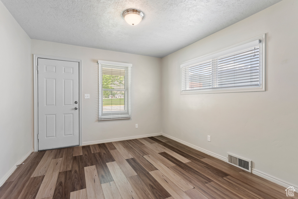 Unfurnished room featuring wood finished floors, a textured ceiling, and baseboards