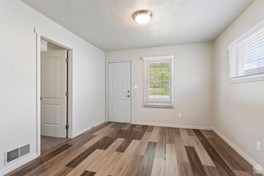 Unfurnished room featuring wood finished floors, a textured ceiling, and baseboards