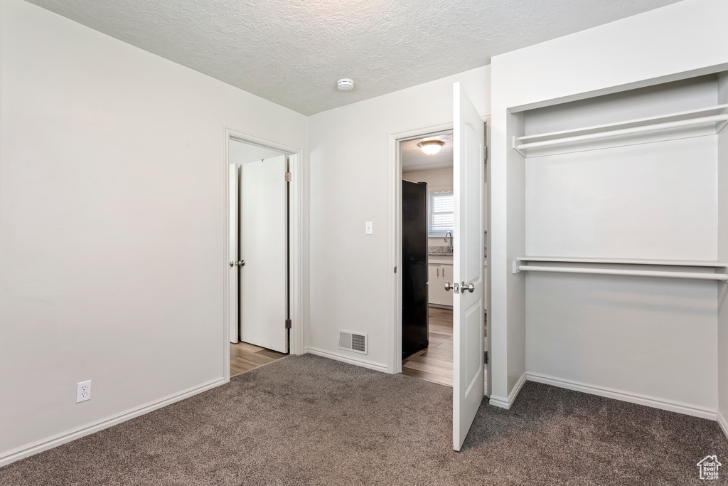 Unfurnished bedroom with carpet, a textured ceiling, and baseboards