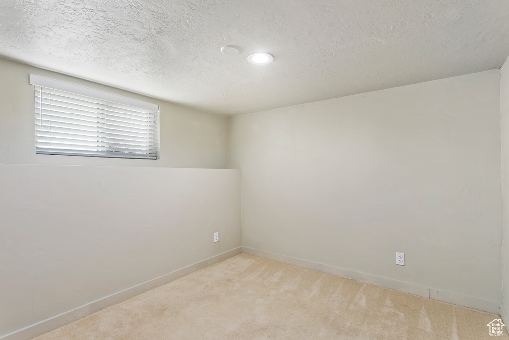 Empty room featuring light carpet, a textured ceiling, baseboards, and recessed lighting