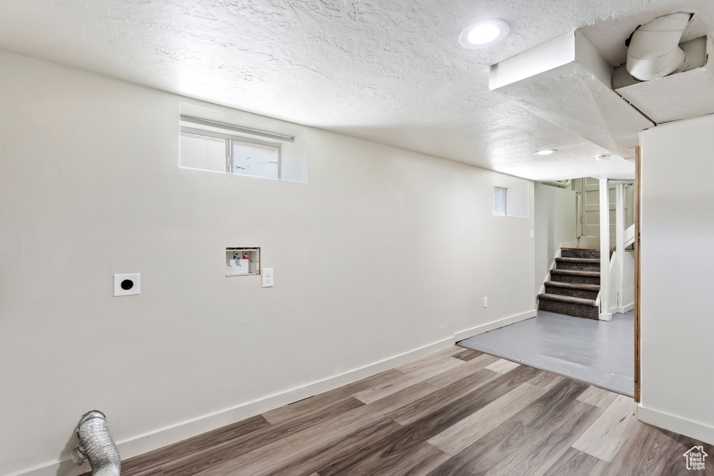 Below grade area featuring a textured ceiling, wood finished floors, stairs, baseboards, and recessed lighting