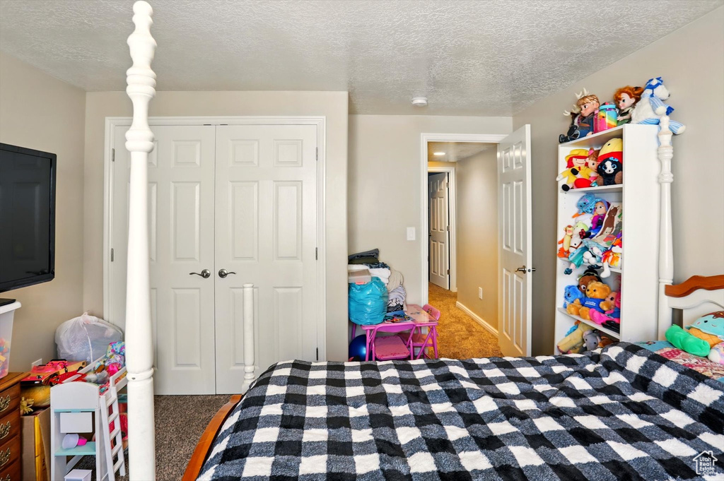 Carpeted bedroom featuring a textured ceiling and a closet