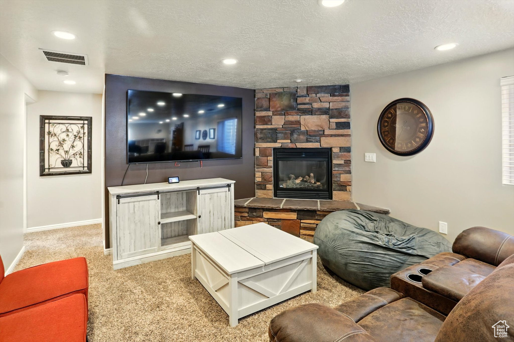 Living area featuring baseboards, a textured ceiling, light carpet, a fireplace, and recessed lighting