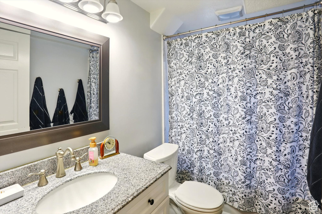 Full bath with toilet, vanity, and curtained shower