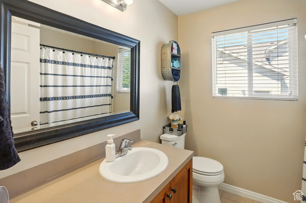 Bathroom with toilet, vanity, baseboards, tile patterned floors, and curtained shower