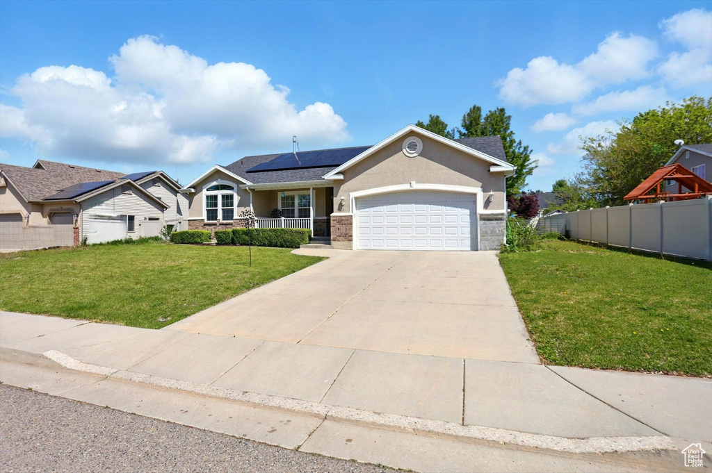 View of front of property featuring solar panels, a garage, driveway, and a porch