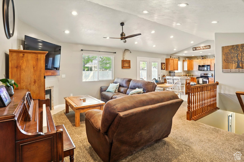 Living area featuring lofted ceiling, ceiling fan, recessed lighting, light carpet, and a glass covered fireplace